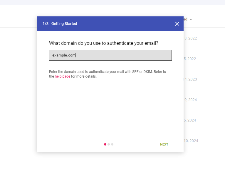 Screenshot of a webpage with a "Getting Started" dialog box asking for a domain to authenticate email. A text field displays "example.com". There is a note below the field about SPF or DKIM, and "NEXT" button at the bottom right. Background shows a blurred list.